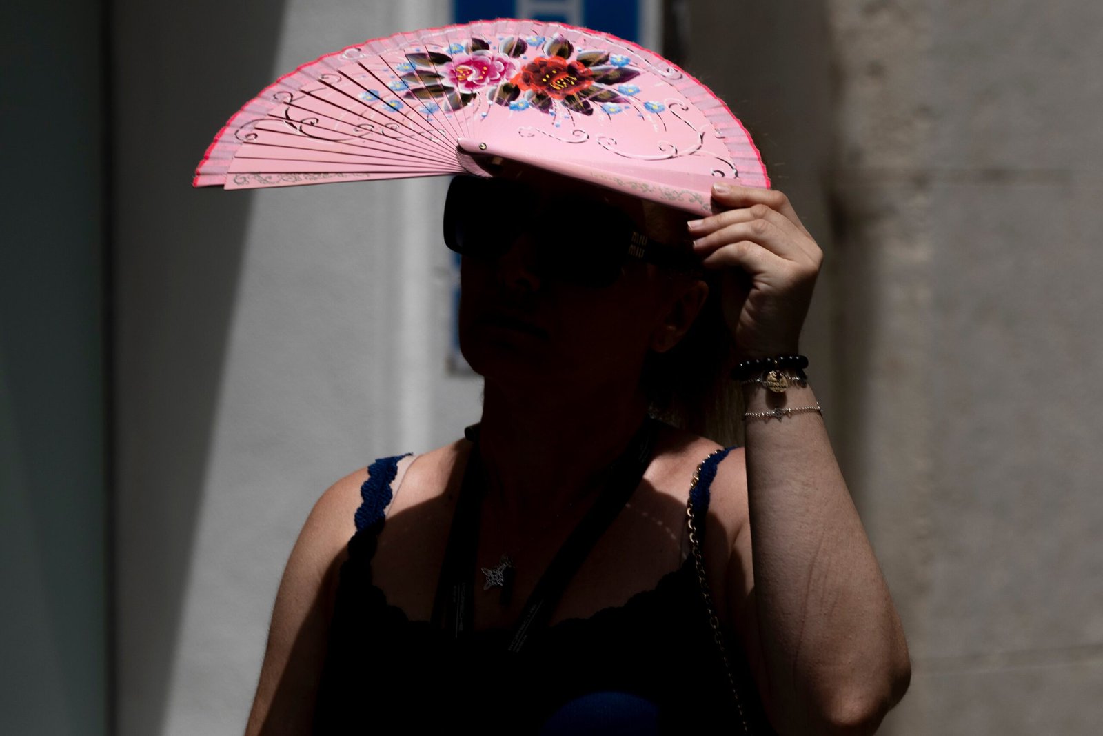 Una persona con un abanico contra el sol en Sevilla.