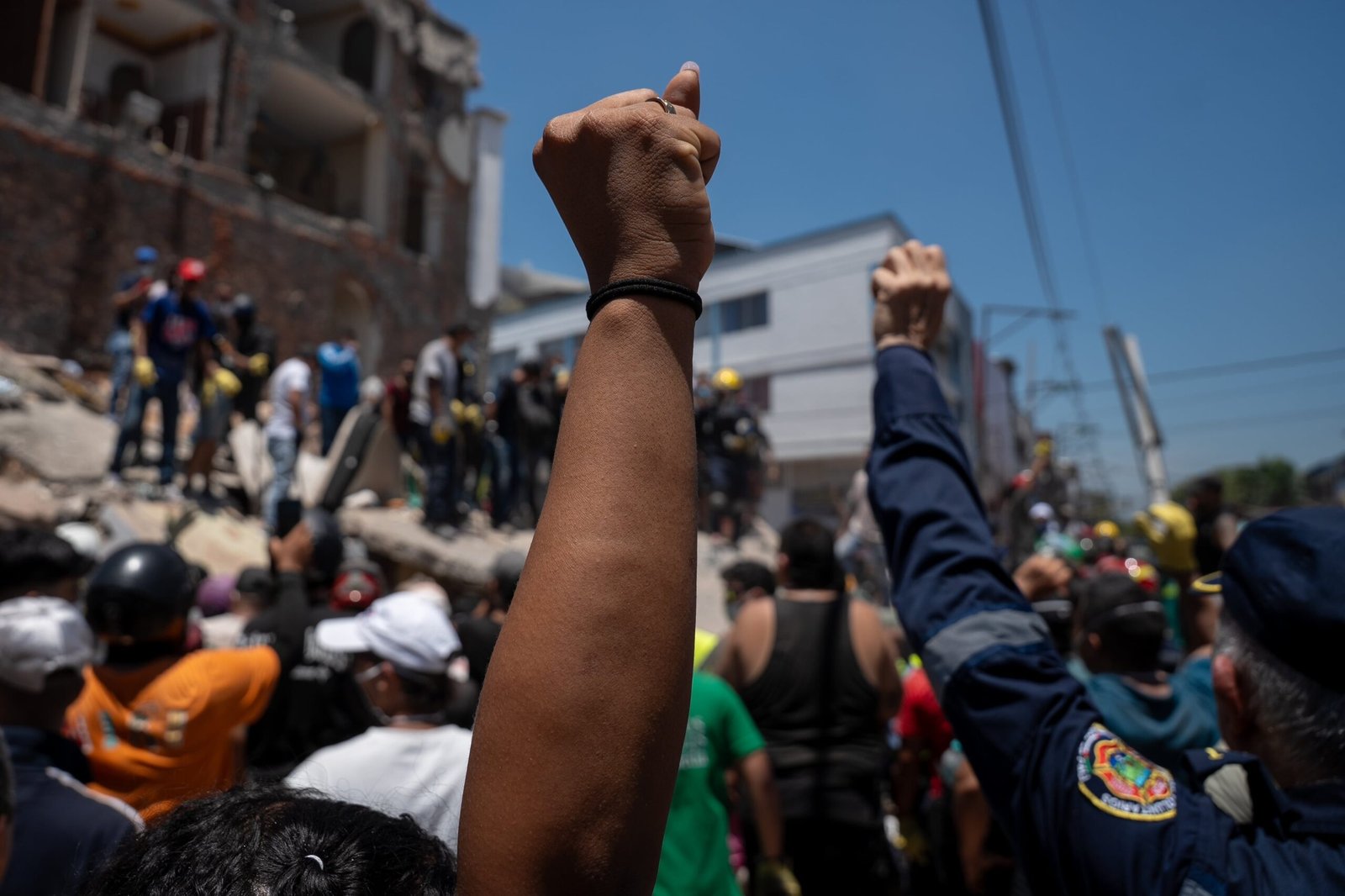 Con el puño en alto piden silencio para escuchar indicios de sobrevivientes en Barrio Alameda, en Cali, Colombia.